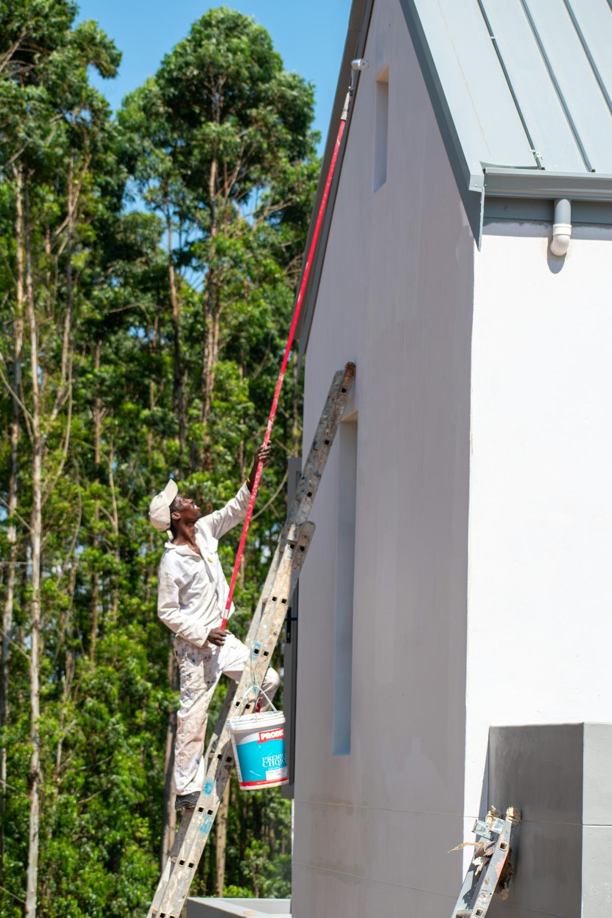 Painter on a ladder painting a house exterior